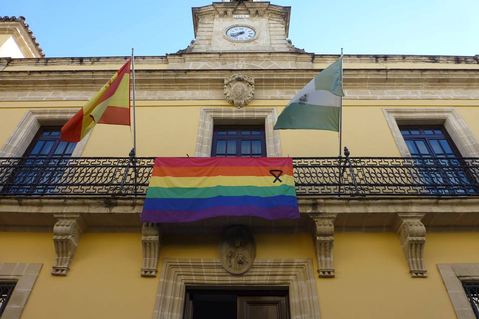 La bandera arcoiris y un lazo negro sobre la fachada de un Ayuntamiento./ JereLesGay